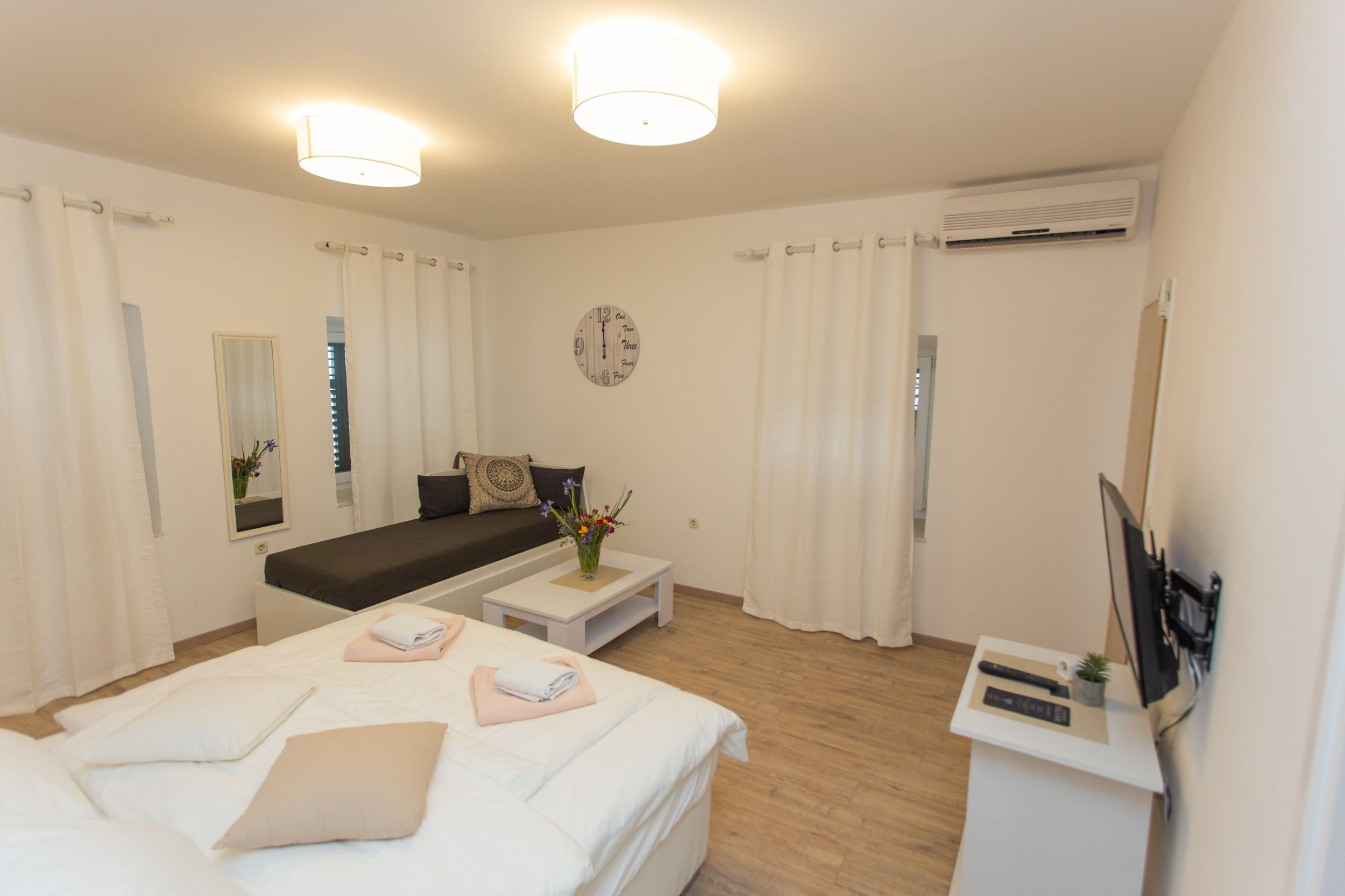 Ein modernes Hotelzimmer mit einem großen Bett, einer Couch, einem kleinen Tisch und einem Fernseher.
