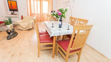 Een eethoek met een tafel gedekt voor vier personen, omringd door houten stoelen met rode kussens.