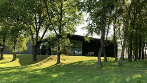 A grassy area with trees and a modern building with large windows. - Hostel Brønderslev (Bronderslev)