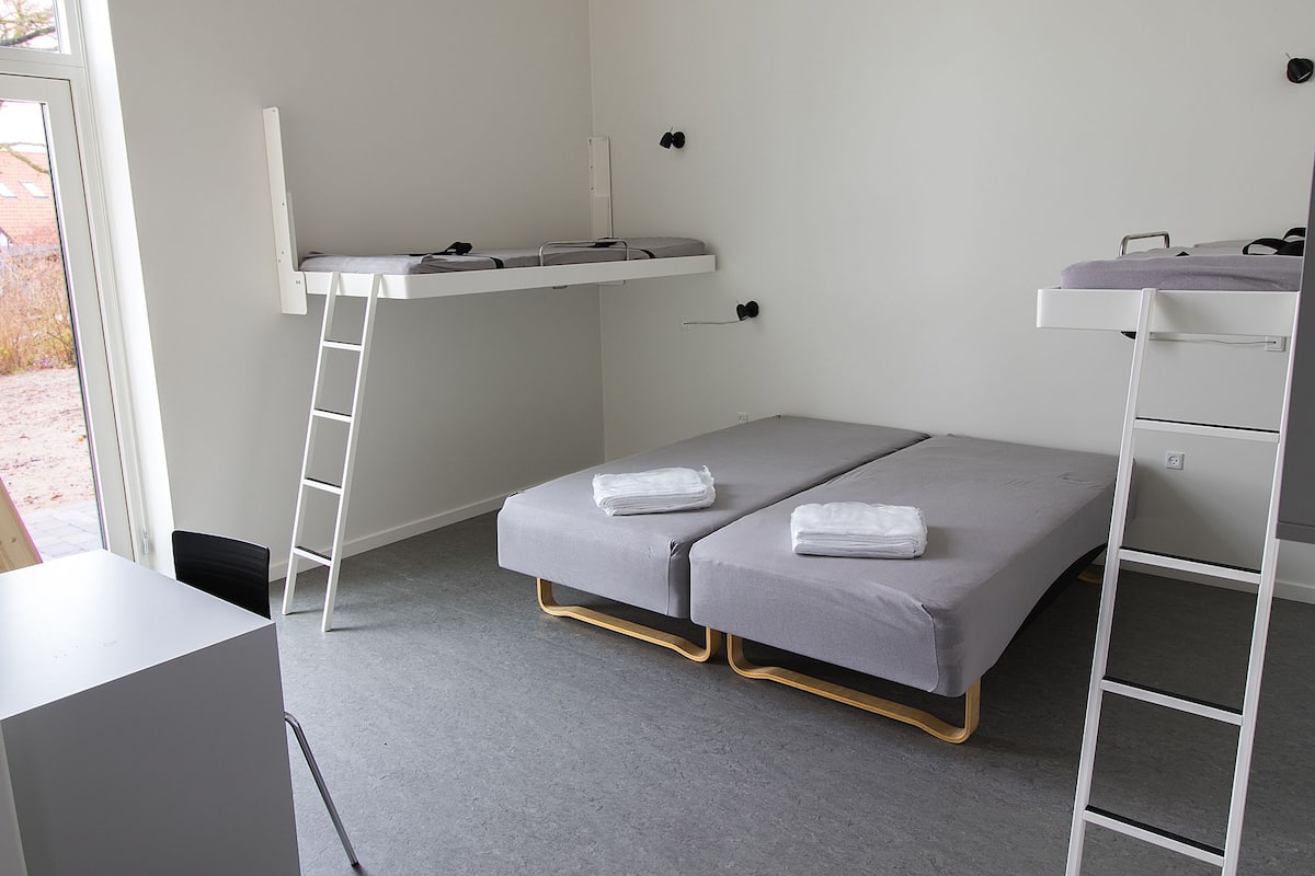 Una habitación pequeña con una litera, un escritorio y una silla.