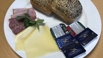 Un plato con rebanadas de pan, queso, jamón, salami y dos paquetes de queso Kergarden.