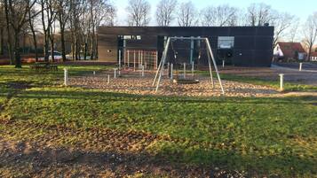 A modern building with a swing set in a park.