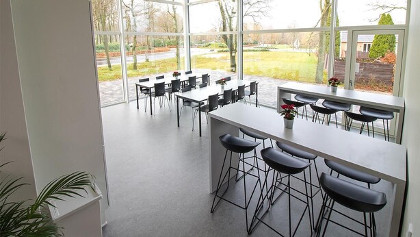 A modern conference room with large windows, a long table, and several bar stools. - Hostel Brønderslev (Bronderslev)