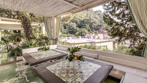 An outdoor seating area with a view of a hillside town. - Green Coral (Capri)
