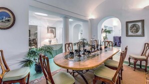 A dining area with a round table, chairs, and decorative items. - Green Coral (Capri)
