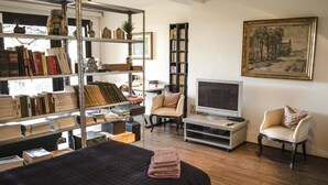 A room with a bed, a TV, a bookshelf, and a chair. - Bed & Breakfast San Lazzaro Room (San Lazzaro di Savena)