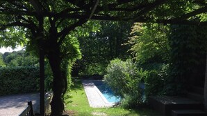 A garden with a paved walkway, a bench, and a pool area surrounded by lush greenery. - Bed & Breakfast San Lazzaro Room (San Lazzaro di Savena)
