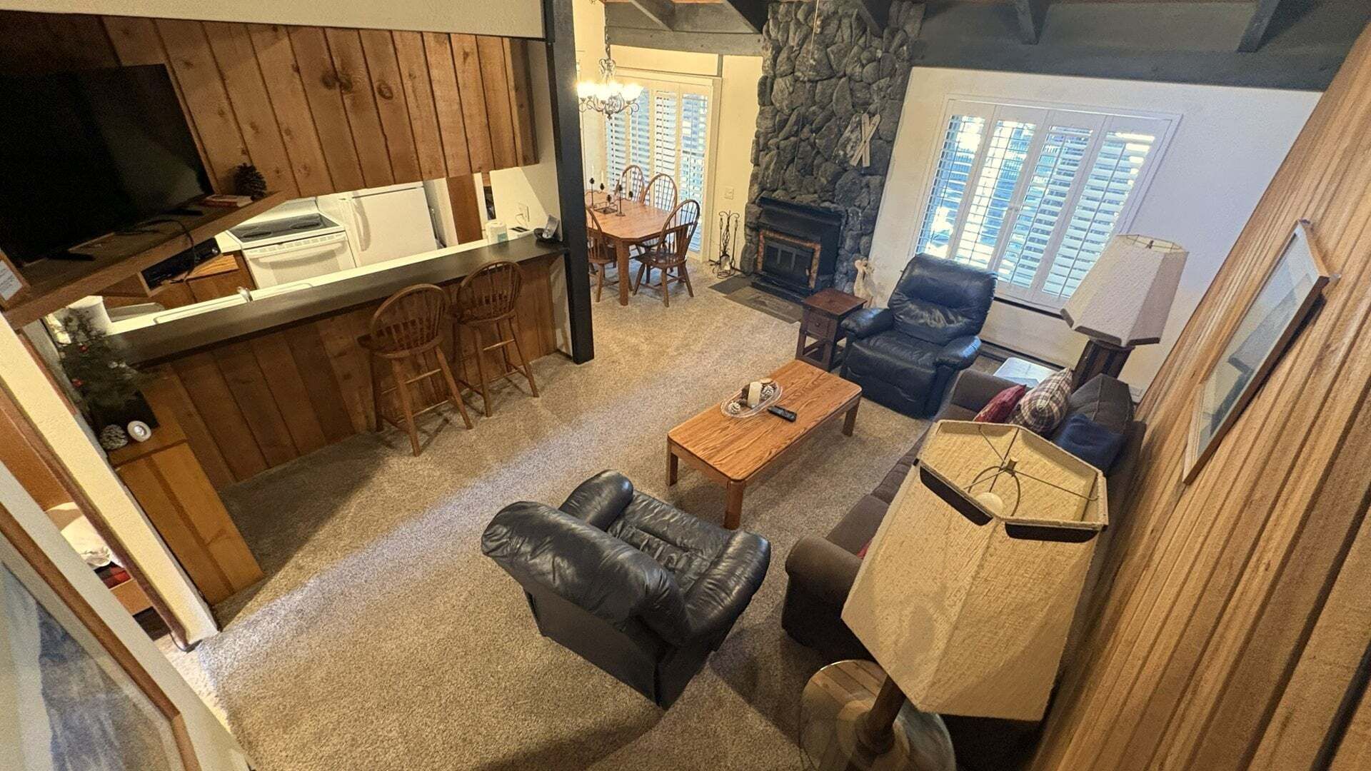 Una sala de estar acogedora con chimenea, sofá de cuero, mesa de centro de madera y una pared de acento de piedra.