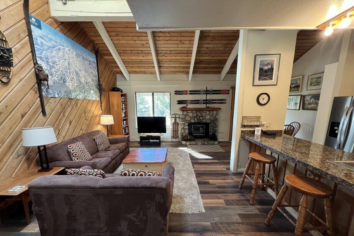 A cozy living room with a sofa and a coffee table, a fireplace, and a dining area with bar stools.