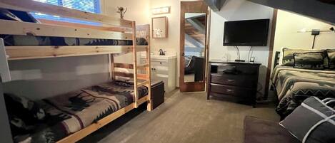 A room with bunk beds, a desk, a television, and a couch.