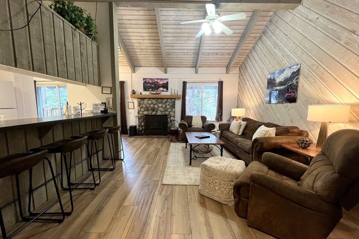 A spacious living area with a fireplace, a bar with stools, and a cozy seating arrangement.