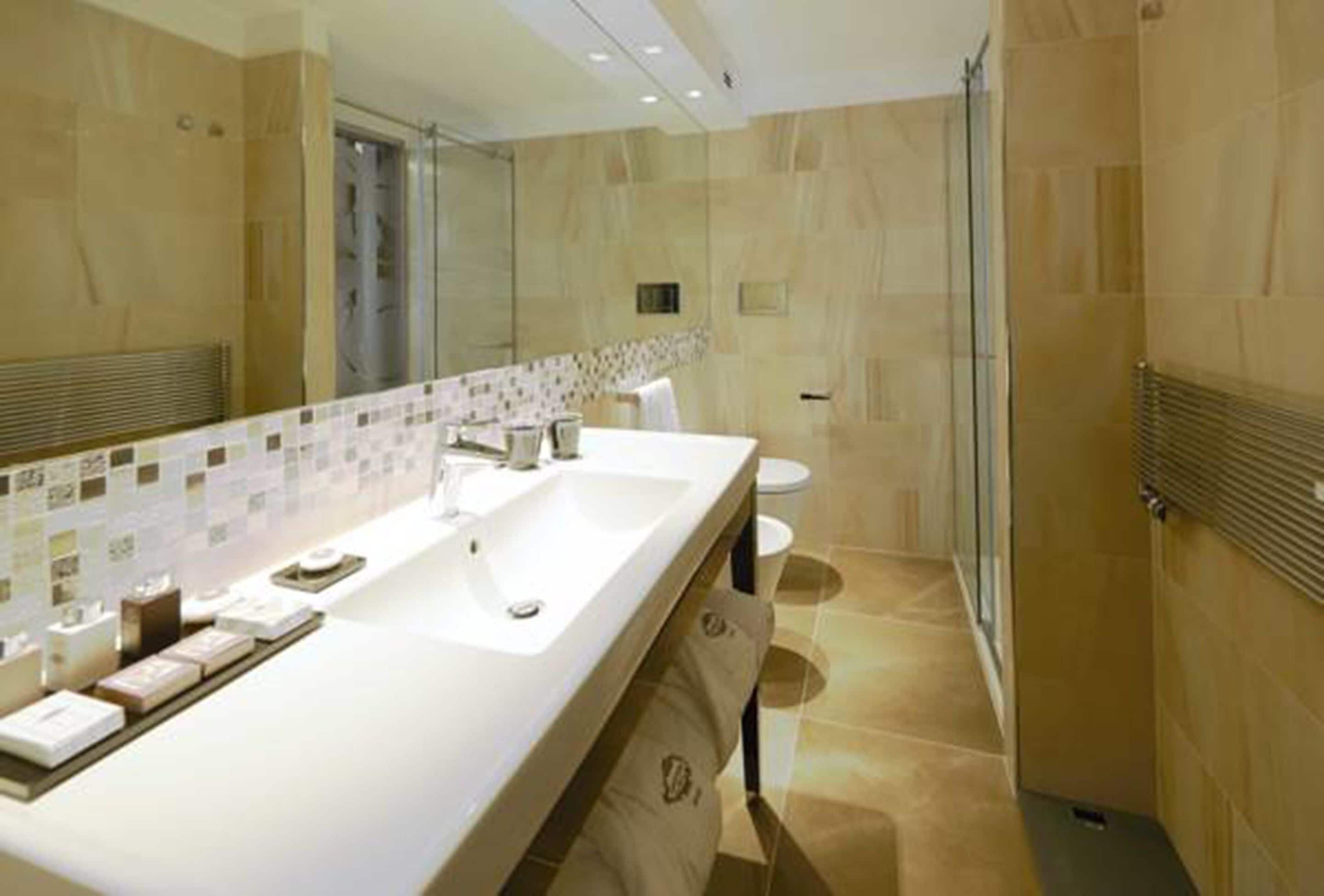 Un bagno moderno con uno specchio grande, due lavandini e una zona doccia.