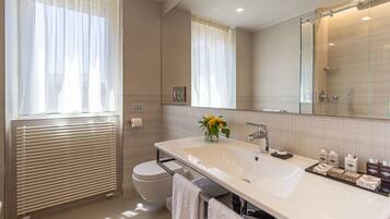 A modern bathroom with a large mirror, a white sink, and a toilet.