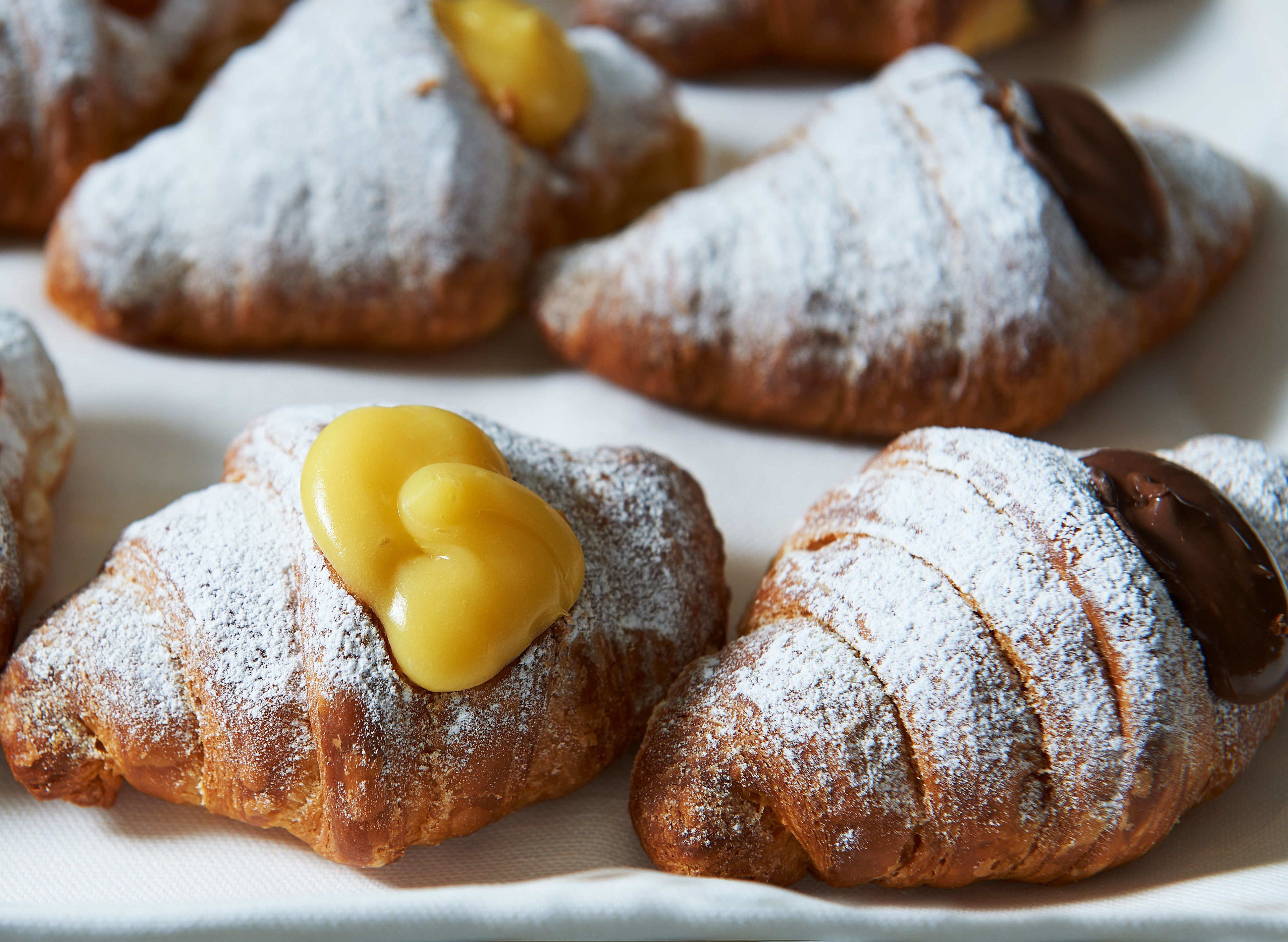 A plate of pastries with powdered sugar and chocolate on top.