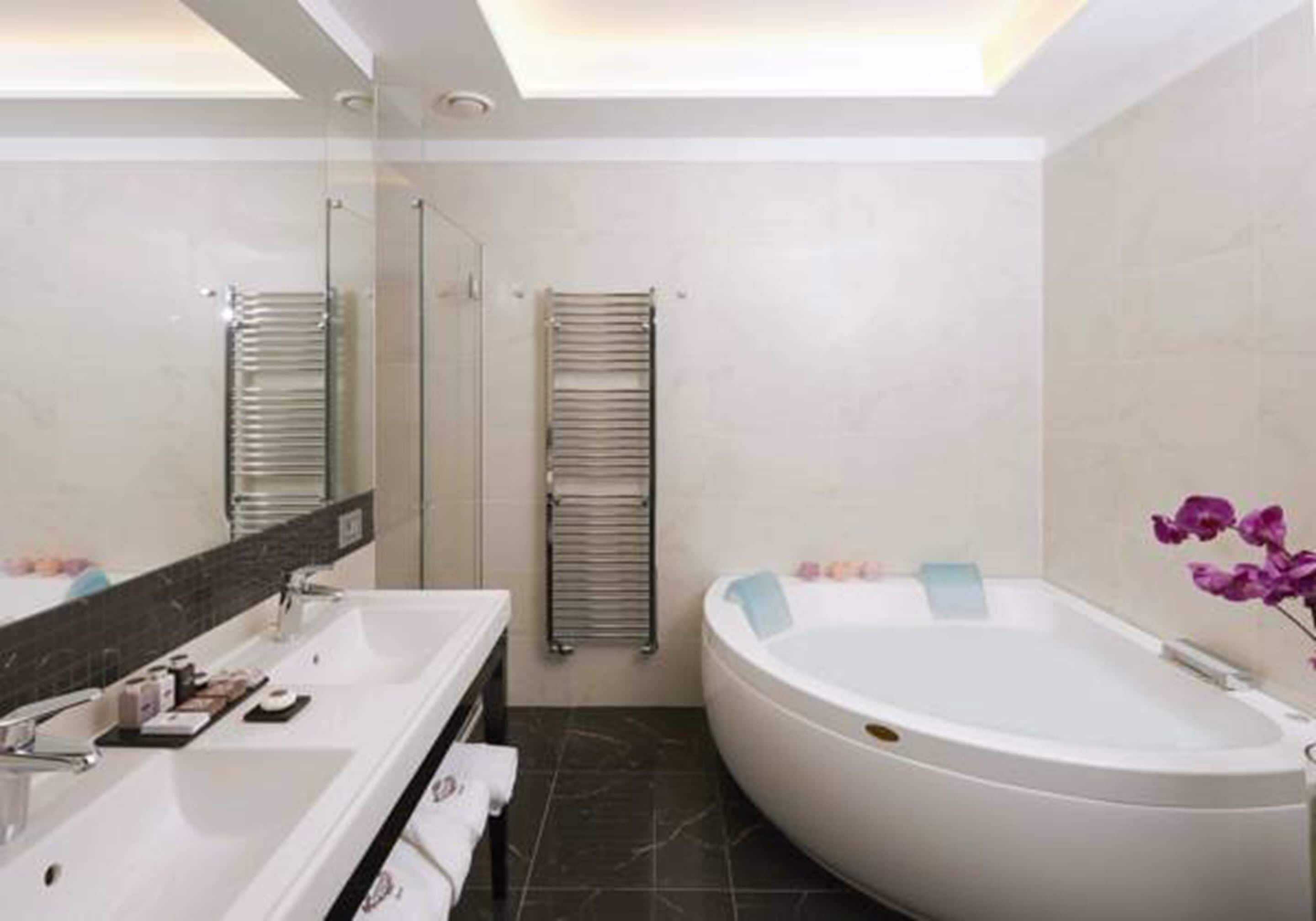 A modern bathroom with a large bathtub, a double sink vanity, and a glass shower enclosure.