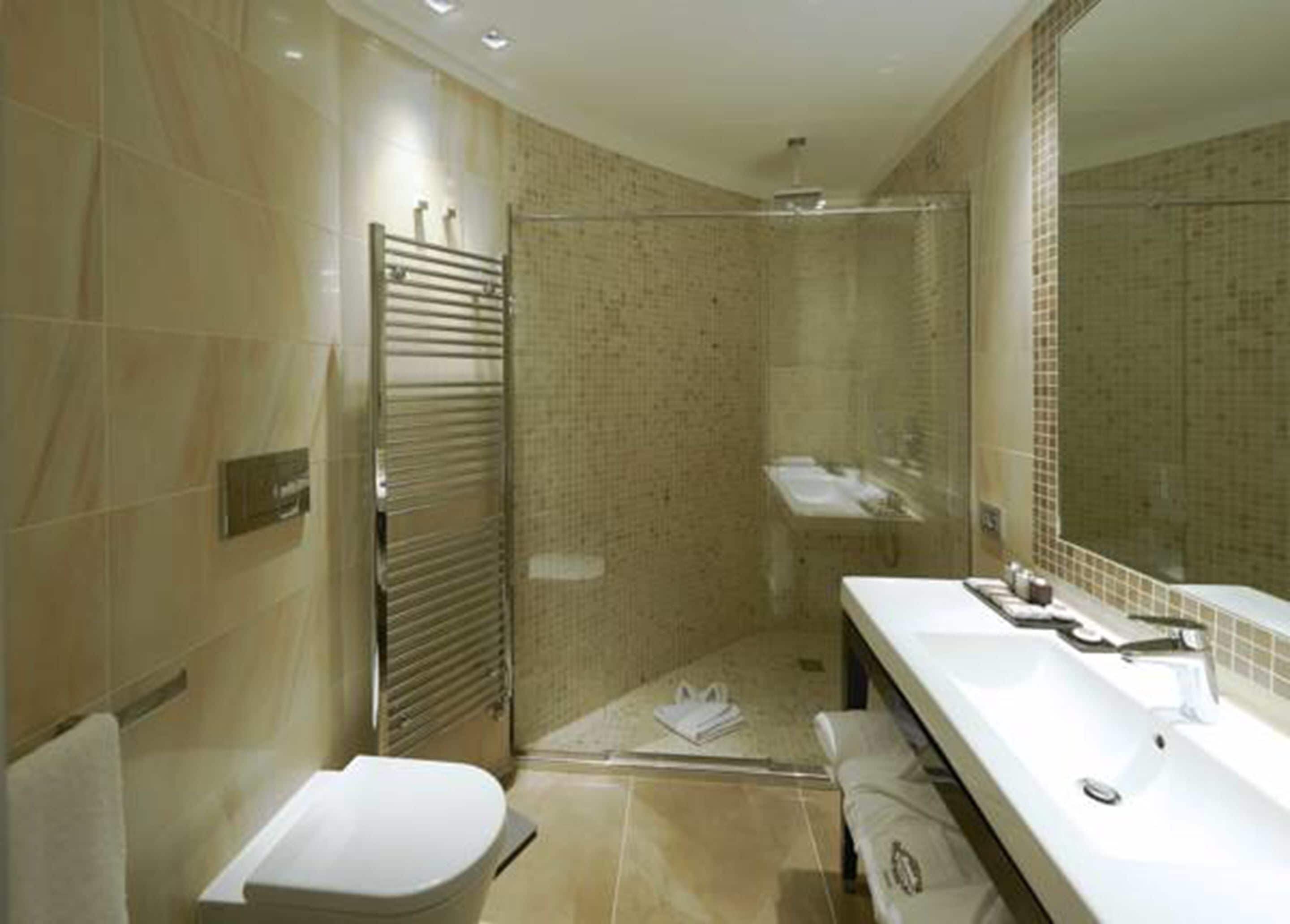 Un baño moderno con ducha a ras de suelo, inodoro y lavamanos con espejo.