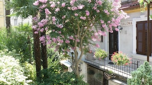 A building with a balcony and a tree with pink flowers.