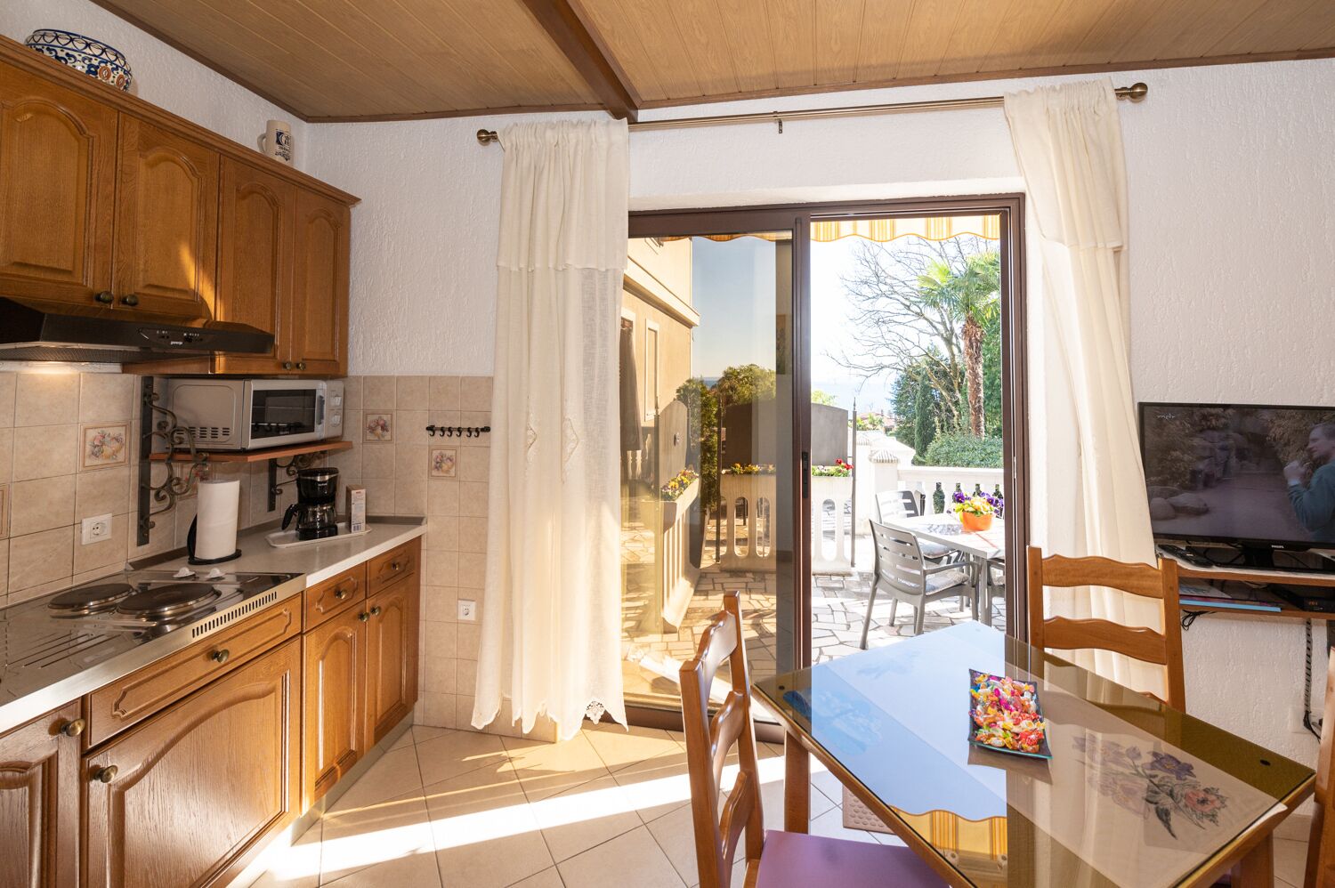 Una cocina con armarios de madera, microondas y comedor con mesa y sillas.