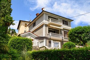 A two-story building with a balcony, surrounded by lush greenery. - Villa Salona (Opatija)