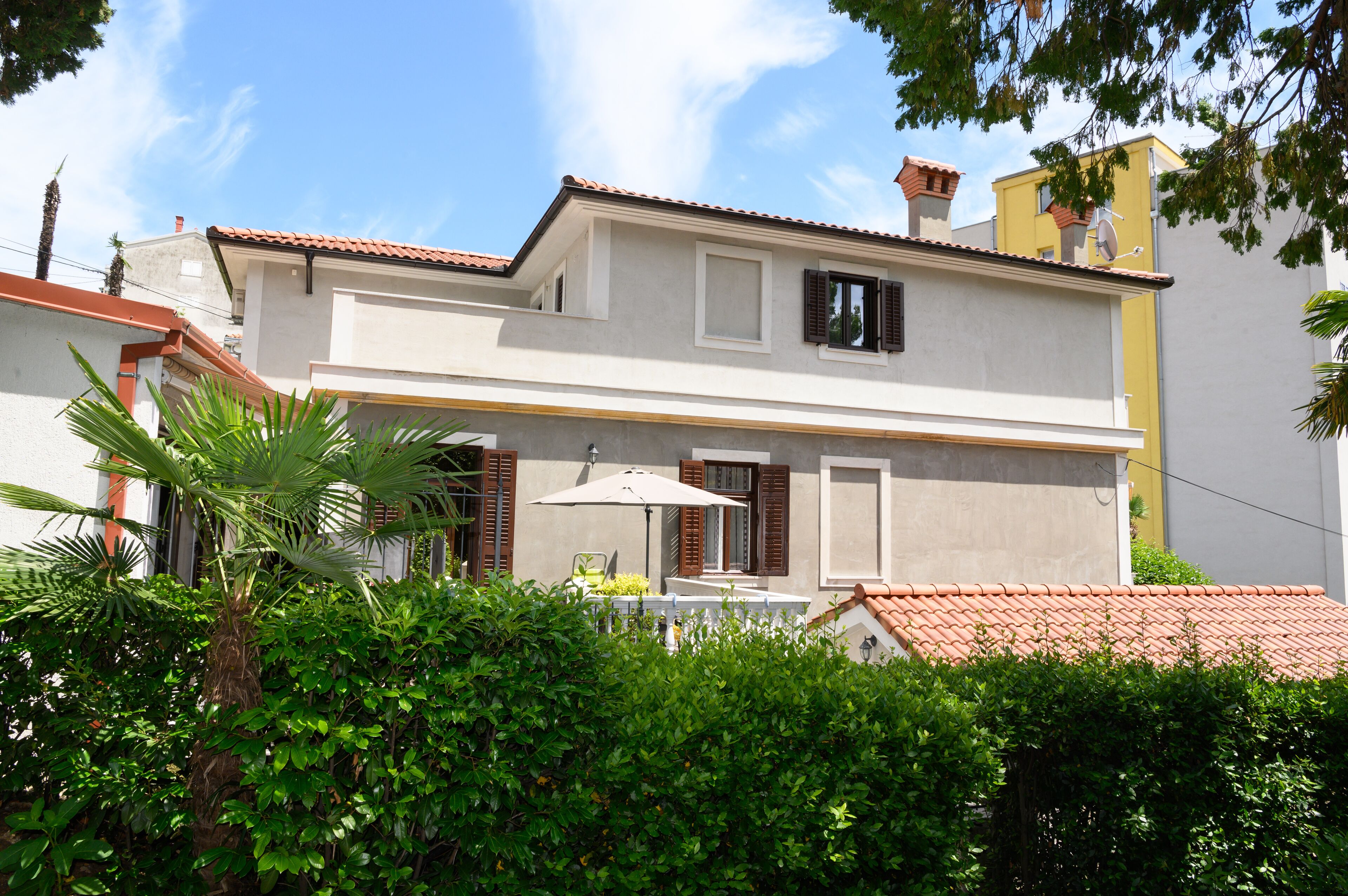 A two-story house with a balcony, a satellite dish, and a red-tiled roof.