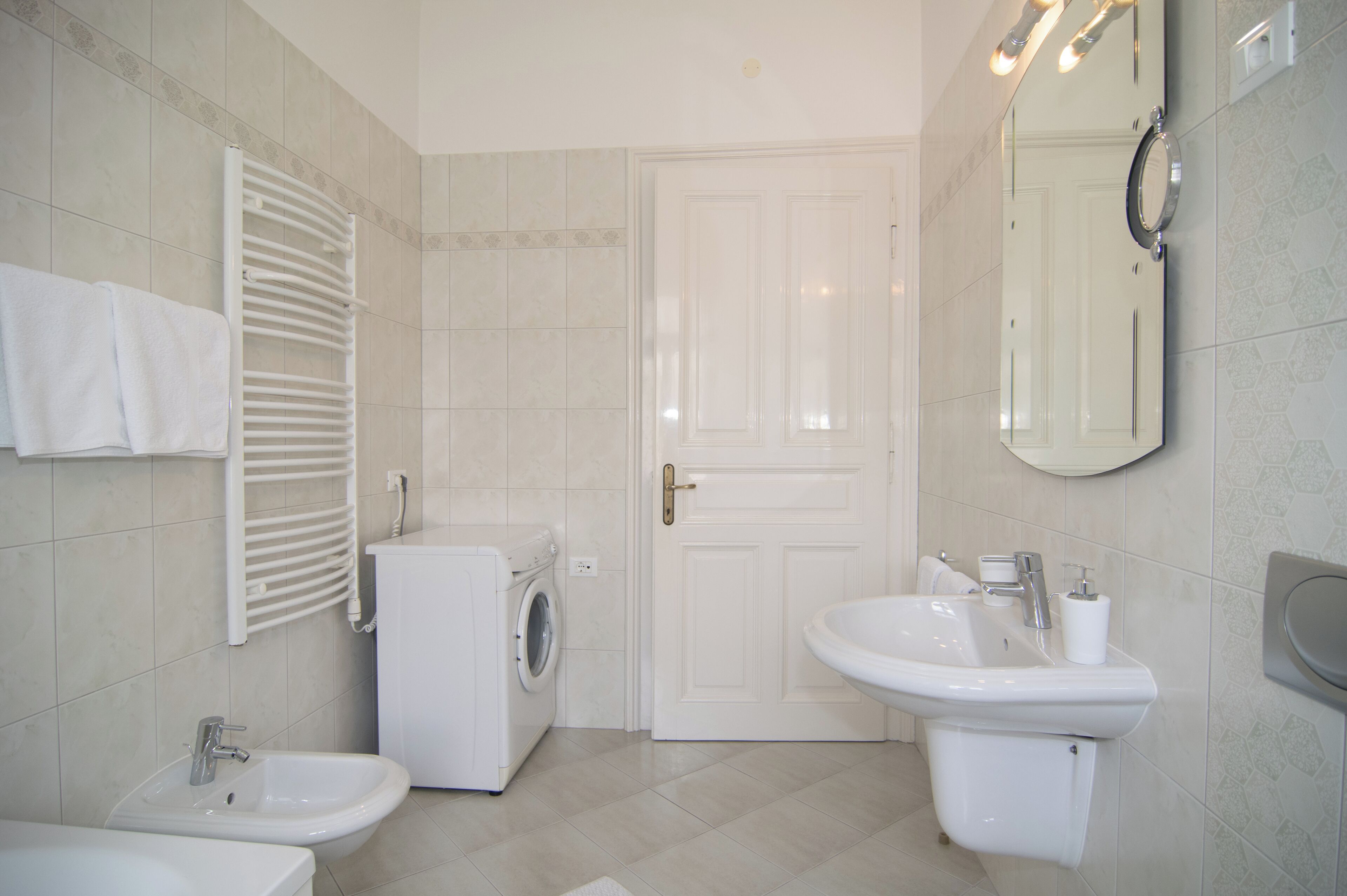 A bathroom with a sink, bidet, and washing machine.