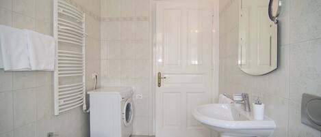 A bathroom with a sink, bidet, and washing machine.