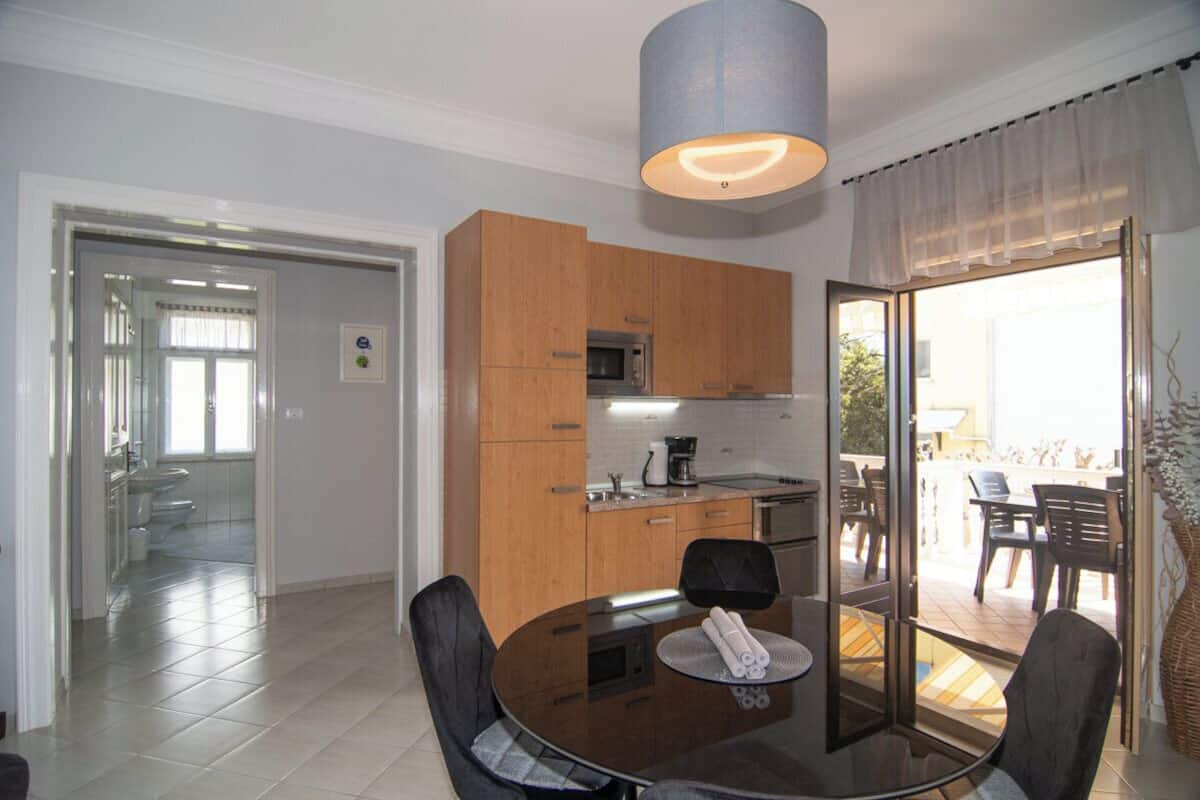 A modern kitchen with wooden cabinets, a round dining table, and a large window.