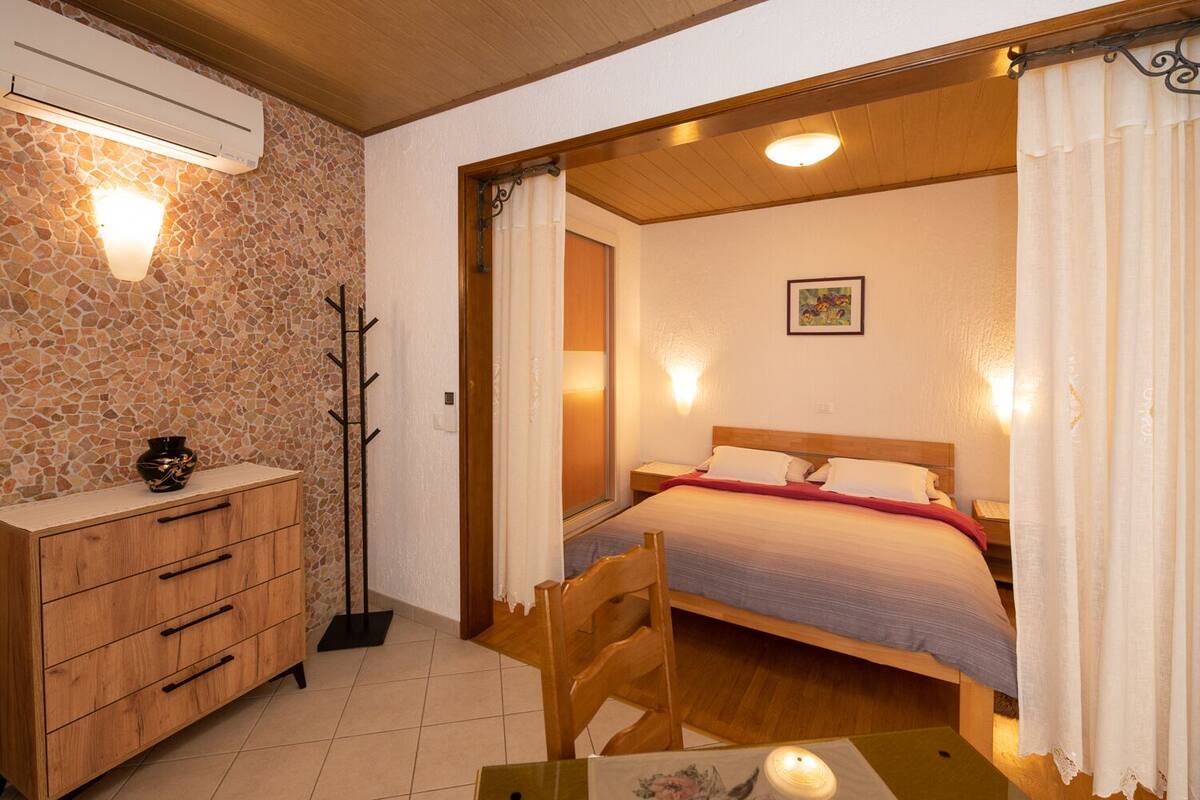 A bedroom with a bed, wooden dresser, and a nightstand.