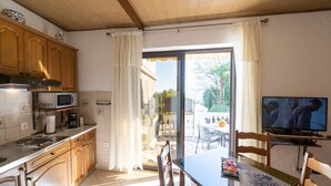 A kitchen with wooden cabinets, a microwave, and a dining area with a table and chairs.