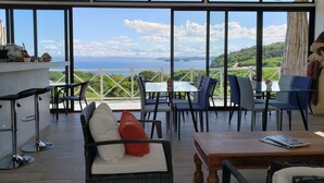 Une terrasse dotée de meubles en osier, d’une table en bois et offrant une vue sur la mer.