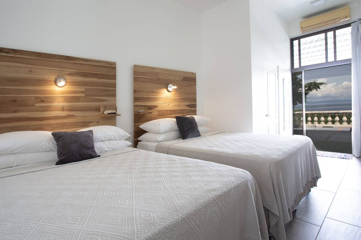 Habitació d'hotel amb dos llits, ambres de fusta i un balcó amb vistes.