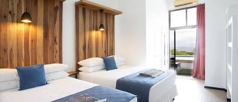 Ett hotellrum med två sängar, trägavlar och utsikt över havet genom ett stort fönster.