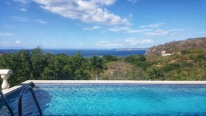 Uma piscina com vista para o oceano e colinas.