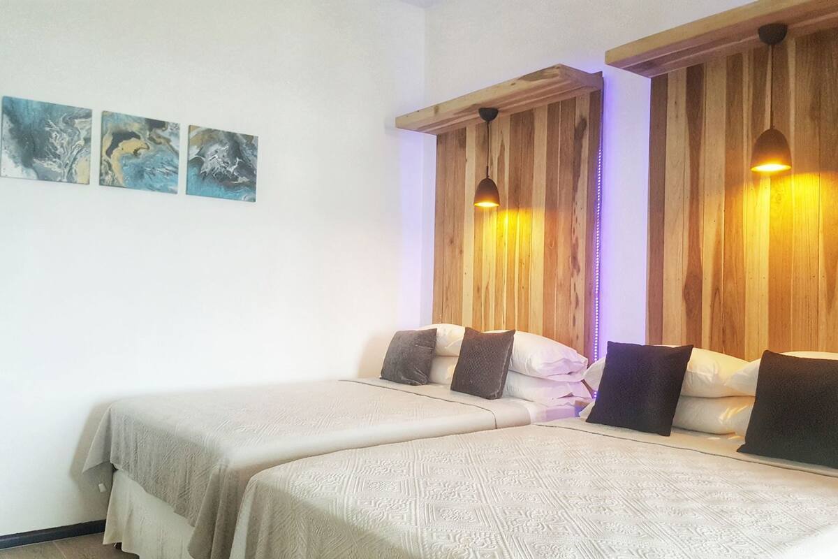 Habitació amb dos llits, parets de fusta i una làmpada al sostre.