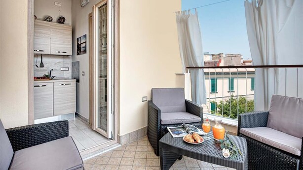 Ein Balkon mit Essbereich, einer Küche und Blick auf die Stadt.