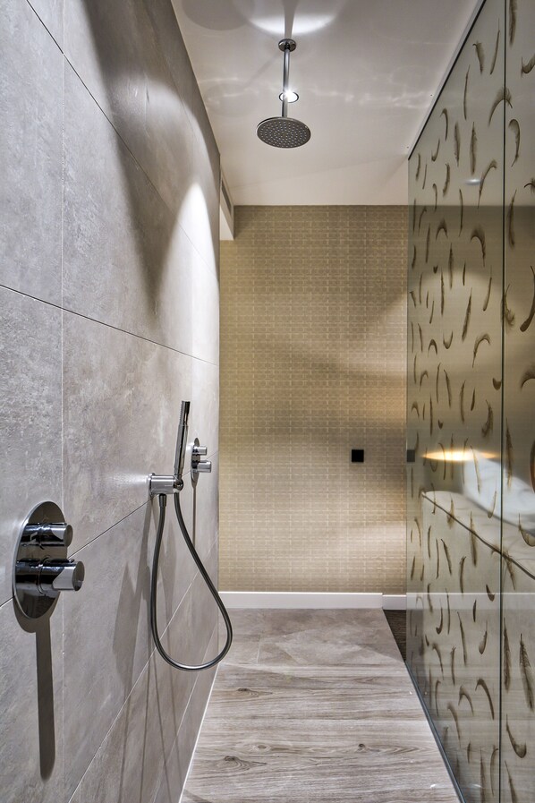 Un baño moderno con ducha, paredes de azulejos y suelo de madera.