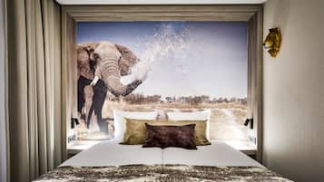 A bedroom with a large bed, a view of an elephant, and a mounted animal head on the wall.