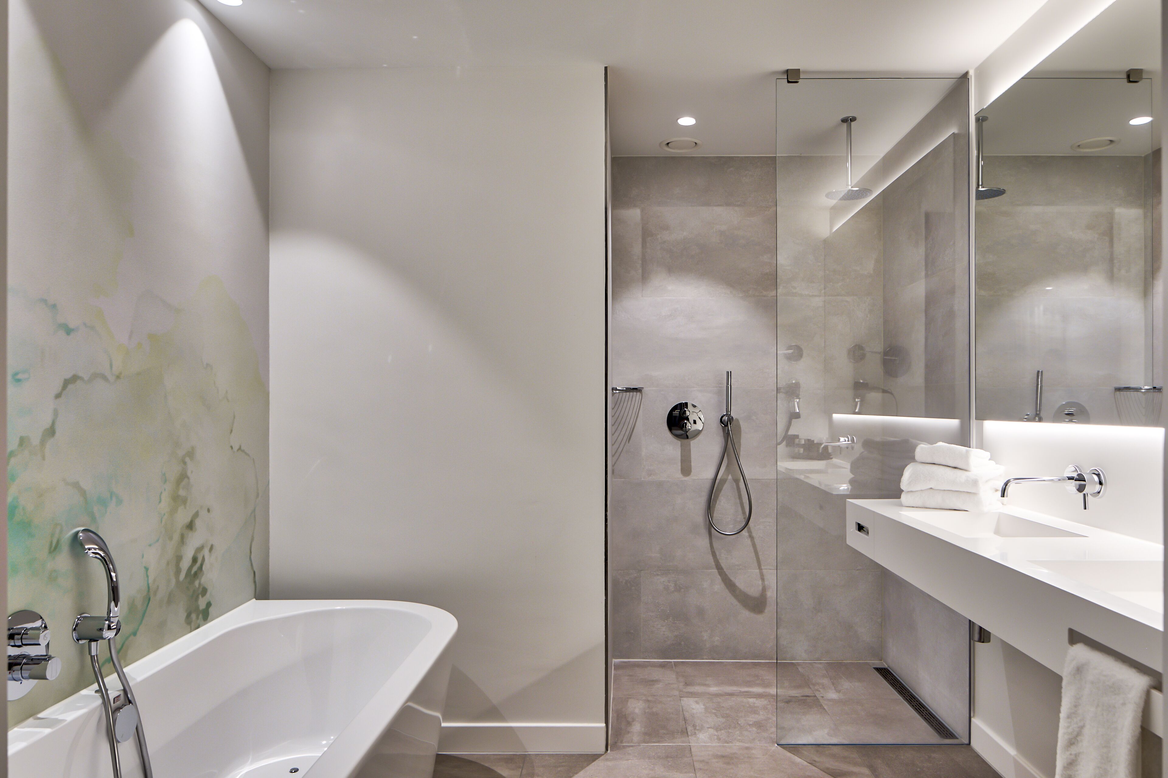 A modern bathroom with a freestanding bathtub, a glass-enclosed shower, and a large mirror above the sink.