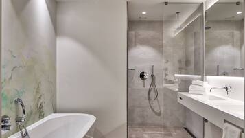 A modern bathroom with a freestanding bathtub, a glass-enclosed shower, and a large mirror above the sink.