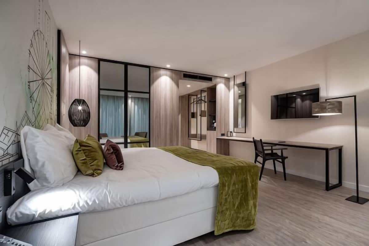 A modern hotel room with a bed, desk, and seating area.
