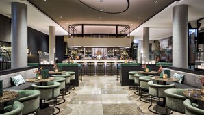 A modern bar area with a central bar, multiple seating options, and a polished floor. - Van der Valk Hotel Tilburg (Tilburg)