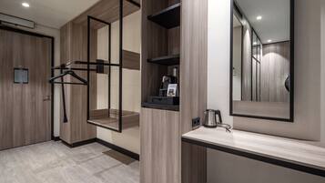 A modern bathroom with wooden cabinetry, a towel rack, a mirror, and a countertop with a kettle.