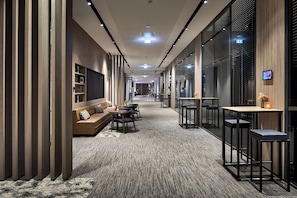A modern hotel lobby with a sofa, chairs, a table, and a bar area.