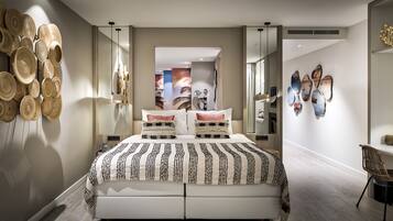 A modern bedroom with a large bed, a bedside table, a chair, and wall art.