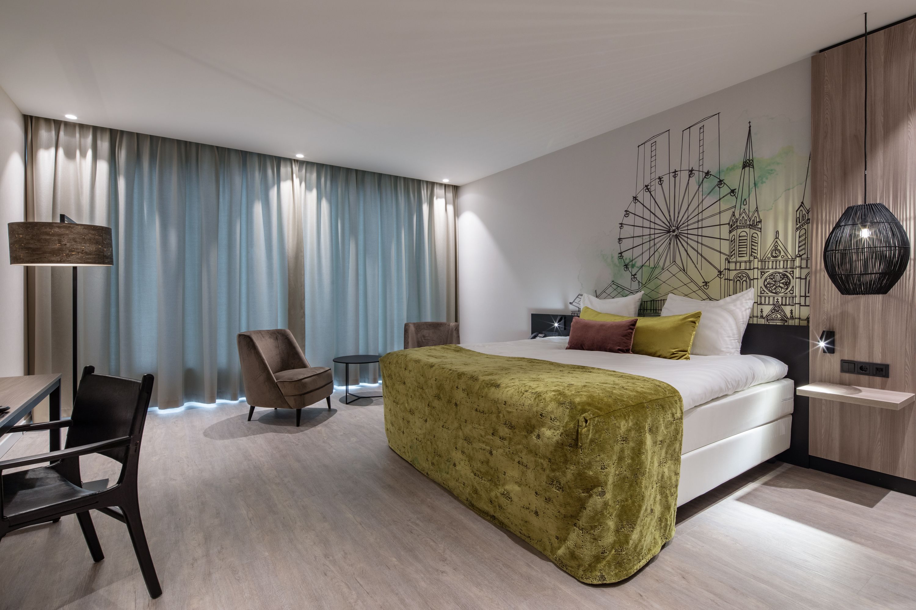 A modern hotel room with a large bed, a desk, a chair, and a wall mural.
