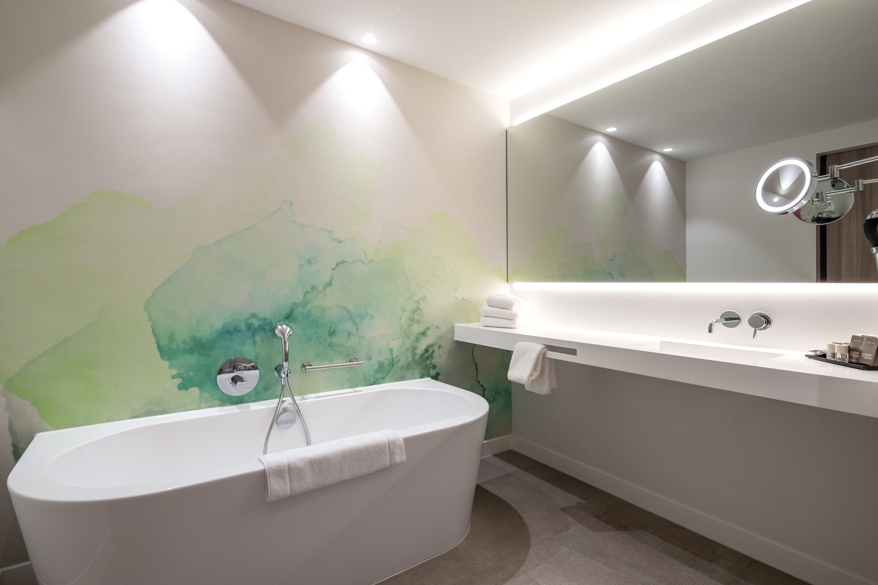 Un baño moderno con una bañera independiente, un espejo grande y un tocador con lavabo.