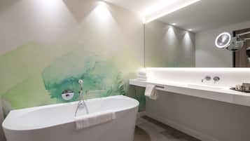 Un baño moderno con una bañera independiente, un espejo grande y un tocador con lavabo.