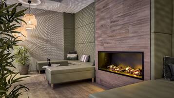 A modern living room with a sectional sofa, a fireplace, and a geometric ceiling design.