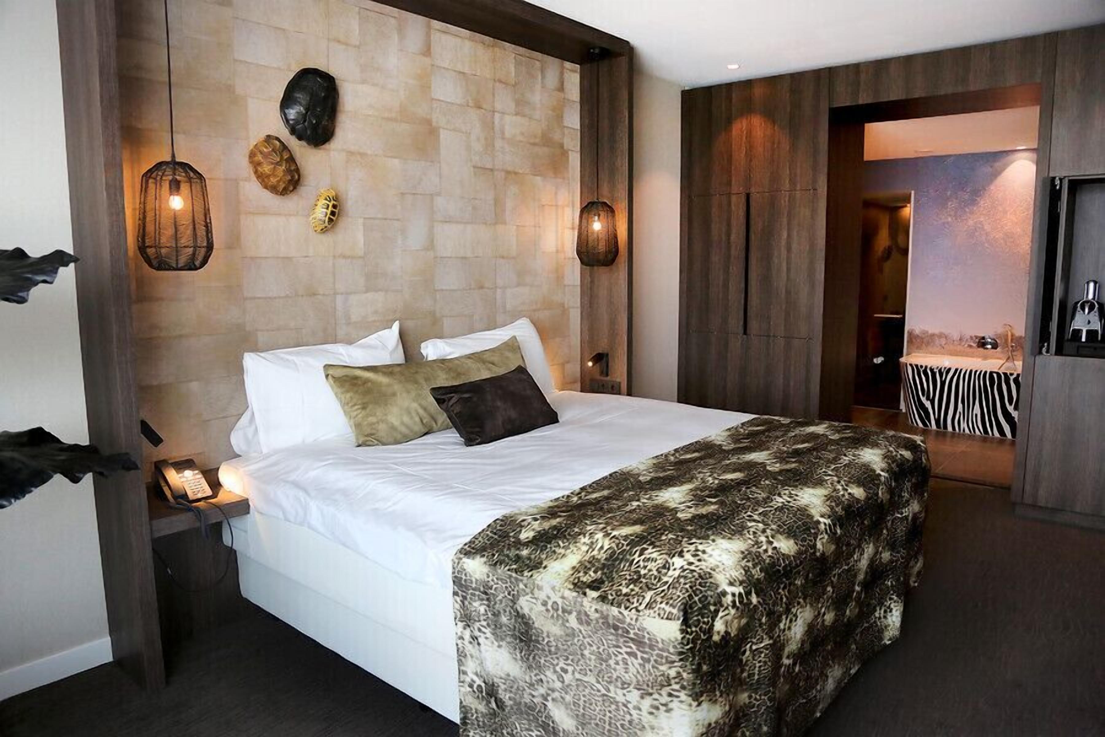 Habitación de hotel con una cama grande, una mesita de noche con teléfono y una lámpara de pared.