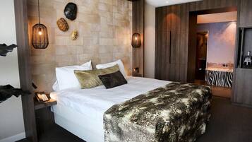 Habitación de hotel con una cama grande, una mesita de noche con teléfono y una lámpara de pared.
